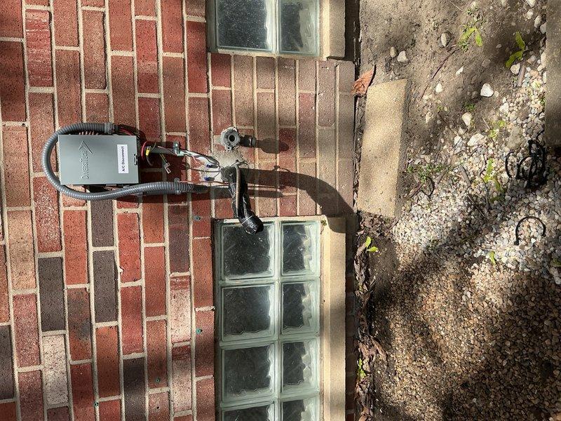 Disconnected and temporarily relocated 10-year-old air conditioning condenser unit from exterior patio location to interior dining room to accommodate customer's patio renovation project. Unit was safely dismounted from exterior wall bracket, refrigerant lines were properly capped and secured, and condenser was positioned indoors per homeowner specifications until patio reconstruction is complete.