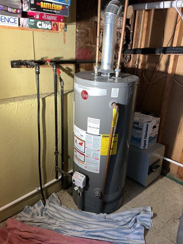 Completed installation of a 40-gallon Rheem tanked water heater in basement utility area. Unit was properly positioned, connected to existing plumbing lines, vented with metallic vent pipe, and equipped with expansion tank. All connections were tested and system was successfully reconnected and operational.