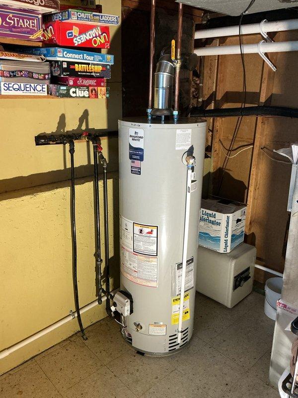 Completed installation of a 40-gallon Rheem tanked water heater in basement utility area. Unit was properly positioned, connected to existing plumbing lines, vented with metallic vent pipe, and equipped with expansion tank. All connections were tested and system was successfully reconnected and operational.