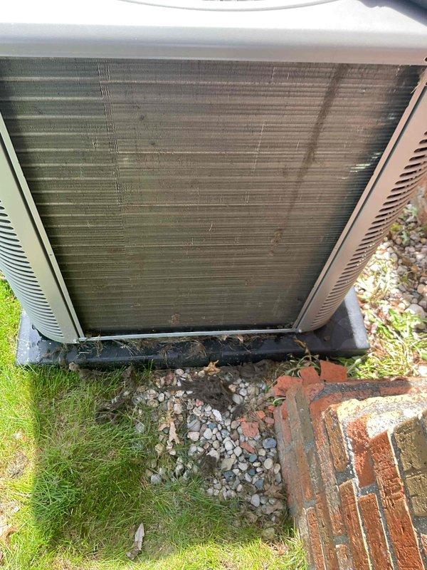 # HVAC Maintenance - Gold AC Inspection

Completed comprehensive Gold-level air conditioning inspection on a 10-year-old Lennox outdoor condensing unit with air handler located in basement. Upon arrival, found condenser coil heavily soiled with substantial accumulation of dirt, dust, and organic debris, with fins showing significant darkening and discoloration throughout. Unit positioned on concrete pad against exterior brick wall with adequate clearance. Performed thorough visual assessment of condenser cabinet, fan grille assembly, and refrigerant line connections. Documented unit condition including exterior panel integrity, mounting stability on pad, and surrounding drainage areas. Electrical disconnect and conduit connections inspected and found secure at wall-mounted junction point. White PVC condensate drain line verified extending from unit top. Captured detailed photographic documentation of coil contamination level and overall equipment condition for service records. Unit ope