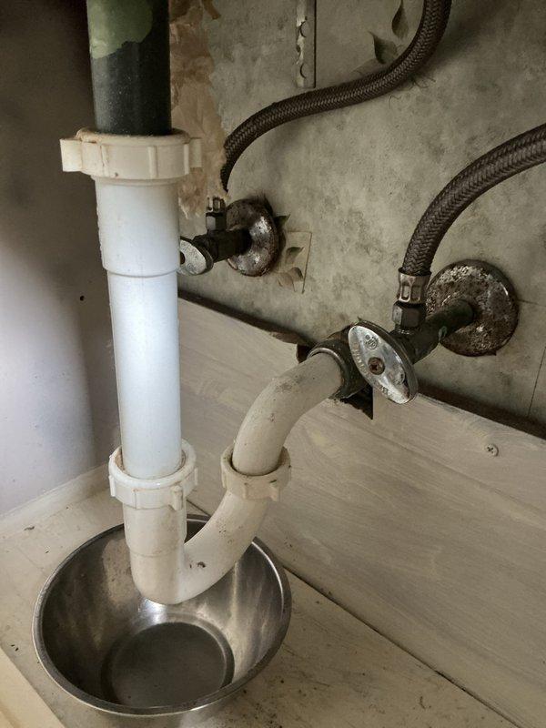 Completed bathroom faucet replacement on white porcelain sink basin. Removed existing faucet assembly and installed customer-provided chrome two-handle faucet with curved spout and decorative lever handles. Connected braided flexible supply lines to existing shutoff valves, verified P-trap assembly for proper drainage, tested system for leaks, and confirmed full functionality of hot and cold water flow.