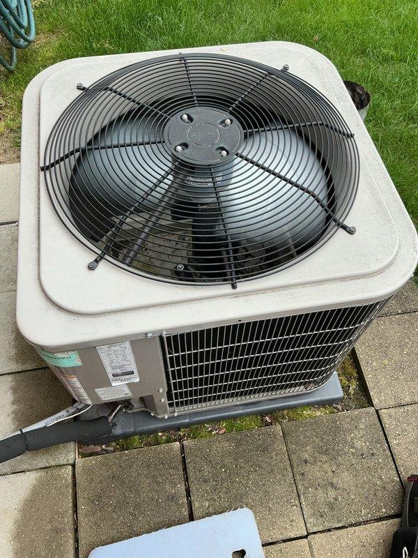# HVAC Maintenance - Gold AC Inspection

Performed comprehensive Gold-level preventive maintenance inspection on an 8-year-old residential split-system air conditioning unit. System was operational upon arrival with air handler and evaporator coil located in basement. Conducted thorough visual assessment of outdoor condenser unit positioned on paver stone patio. Inspected exterior cabinet condition, noting minimal weathering consistent with age and outdoor exposure. Evaluated condenser coil fins and louvers for debris, damage, and airflow obstruction. Examined top-mounted fan assembly and protective wire guard for proper installation and structural integrity. Verified manufacturer's data plate visibility and legibility for future service reference. Assessed refrigerant line connections and electrical disconnect for secure mounting and proper insulation. Confirmed adequate clearance around unit for proper airflow and serviceability. Documented equipment condition through photographic re