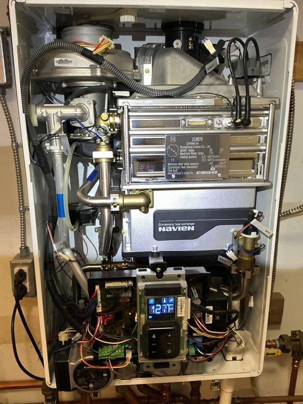 Performed comprehensive tune-up and inspection on Navien tankless water heater located in utility room. Unit was operational upon arrival with display reading 42°F. Removed front access panel and conducted thorough internal inspection of all major components including primary and secondary heat exchangers, gas valve assembly, control board, and digital interface module. Verified proper operation of combustion system, checked all electrical connections and wiring harnesses, inspected heat exchanger surfaces for scale buildup or corrosion, and examined condensate drain system. Tested water flow sensors, temperature sensors, and safety controls for proper function. Inspected all copper and PVC supply and return piping, brass fittings, and isolation valves for leaks or deterioration. Verified proper venting connections and checked exhaust system integrity. System operating within normal parameters at time of service completion.