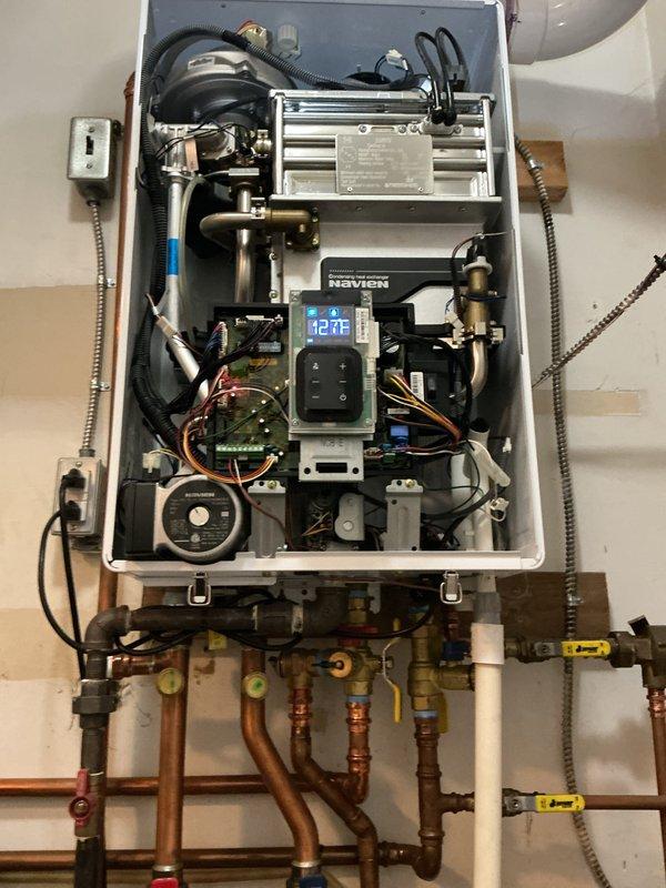 Performed comprehensive tune-up and inspection on Navien tankless water heater located in utility room. Unit was operational upon arrival with display reading 42°F. Removed front access panel and conducted thorough internal inspection of all major components including primary and secondary heat exchangers, gas valve assembly, control board, and digital interface module. Verified proper operation of combustion system, checked all electrical connections and wiring harnesses, inspected heat exchanger surfaces for scale buildup or corrosion, and examined condensate drain system. Tested water flow sensors, temperature sensors, and safety controls for proper function. Inspected all copper and PVC supply and return piping, brass fittings, and isolation valves for leaks or deterioration. Verified proper venting connections and checked exhaust system integrity. System operating within normal parameters at time of service completion.