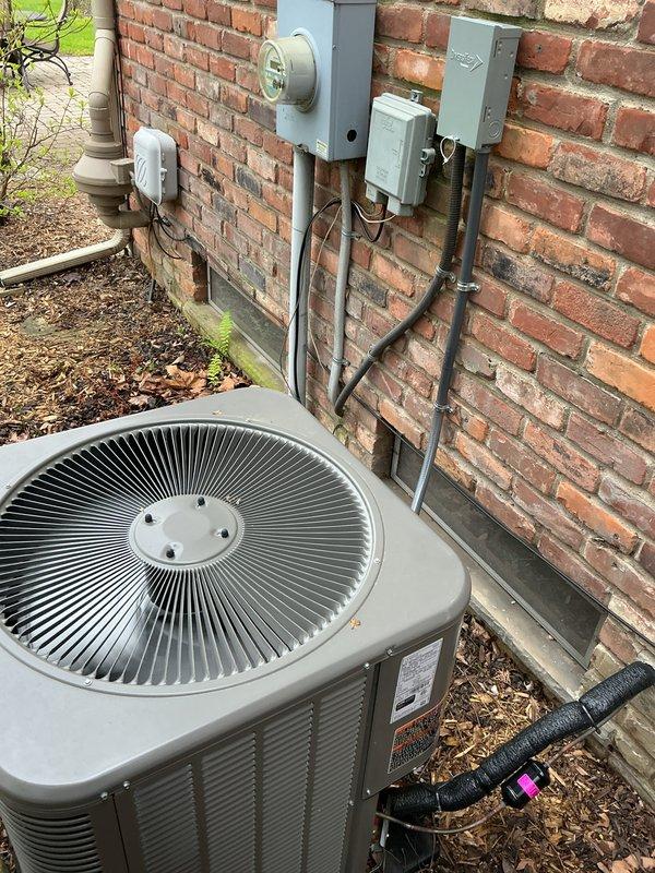 Completed comprehensive Gold Plan inspection on residential HVAC system including furnace and air conditioning unit. Performed thorough tune-up and safety inspection of gas furnace with visual confirmation of proper burner ignition and flame characteristics showing appropriate blue flame pattern across all burners. Inspected gas valve assembly, electrical connections, and blower motor components for proper operation. Evaluated outdoor condenser unit positioned on concrete pad against exterior brick wall, checking refrigerant line connections, electrical service components including meter and junction boxes, and overall system condition. Documented equipment status through photographs showing active furnace operation and exterior unit installation. All components operating within normal parameters at time of inspection.