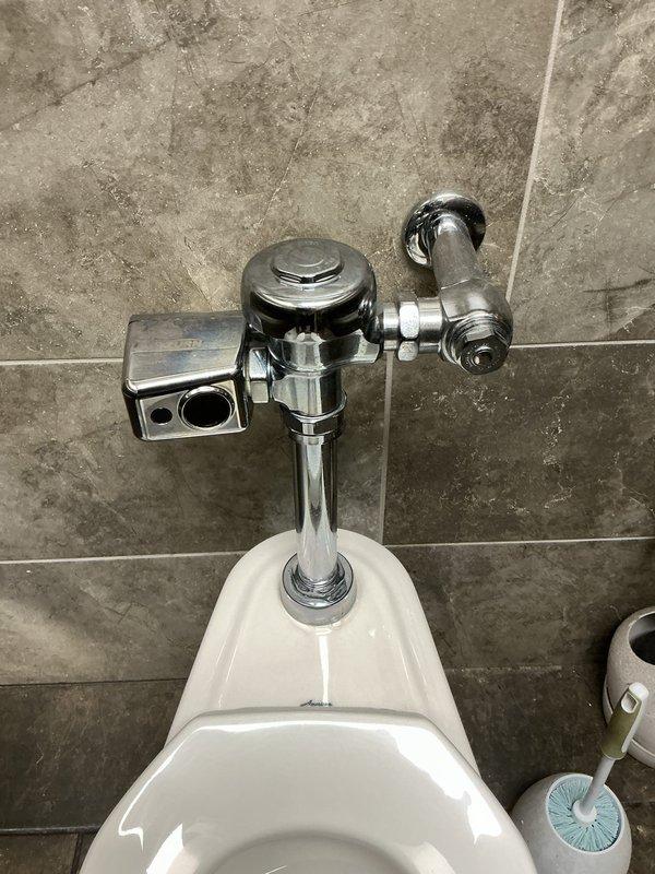 Responded to commercial men's restroom for two non-flushing toilets with leaking flush valves. Inspected both wall-mounted toilet fixtures and identified malfunctioning automatic and manual flush valve systems causing operational failures and water leakage from top valve assemblies. Repaired flush valve mechanisms, replaced faulty internal components, and tested both fixtures to restore proper flushing function and eliminate leaks. All chrome plumbing components and water supply lines verified for proper operation and leak-free performance.