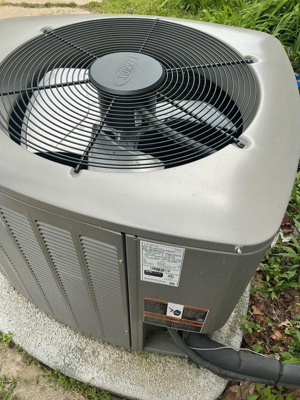 Completed NSP air conditioning inspection on 2-year-old system with coil located in utility room. Unit inspected as part of back-to-back service call arrangement for two properties on same street. Outdoor condensing unit found in excellent operating condition with no visible signs of wear, damage, or deterioration. All components including fan assembly, protective grilles, cabinet panels, and ventilation louvers inspected and confirmed to be functioning properly. Unit properly positioned on concrete pad with adequate clearance and drainage. System photographed and documented for service records.