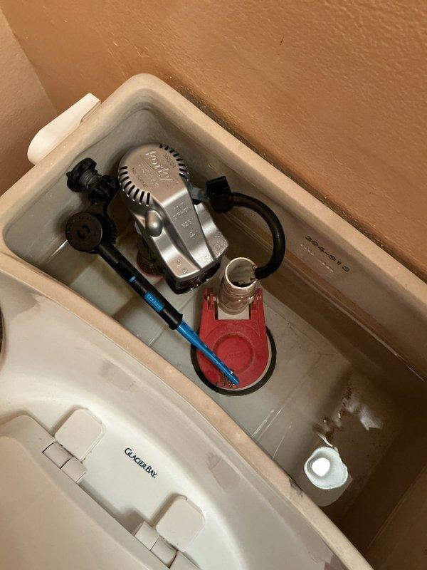 Responded to complaint of low water level in main floor toilet that continued dropping with air bubbles present after customer returned from vacation. Inspected toilet tank and bowl assembly, identifying internal component malfunction causing water loss and air infiltration. Removed tank lid and examined flush valve, flapper assembly, and fill valve mechanism. Adjusted Fluidmaster fill valve settings and replaced defective red flapper valve that was allowing water to slowly leak from tank into bowl. Verified proper seal on flush valve seat and confirmed refill tube was properly positioned in overflow tube. Tested flush cycle multiple times to ensure proper water level restoration and elimination of air bubbles in bowl. Verified toilet now maintains consistent water level without further loss.