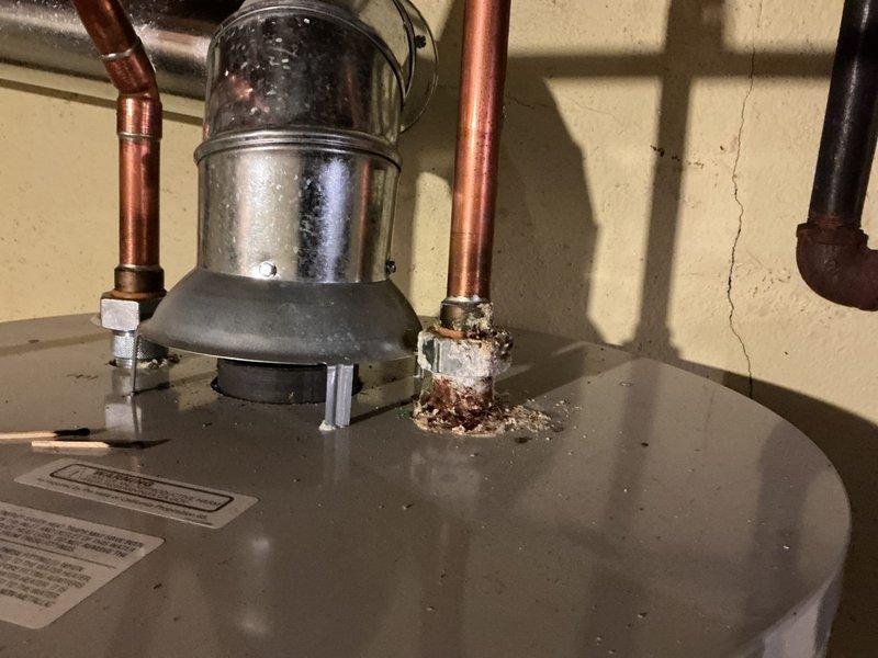 Responded to service call for corroded water heater outlet requiring repair prior to municipal inspection. Upon arrival, found significant corrosion and rust buildup at the hot water outlet connection on top of tanked water heater, with deterioration visible around the threaded fitting and copper piping. Assessed the extent of corrosion damage to determine appropriate repair method to bring unit into compliance with code requirements. Documented existing conditions showing compromised outlet connection with brown and reddish-orange oxidation at the fitting junction. Evaluated water heater plumbing system including inlet and outlet connections, shut-off valves, and associated copper piping to ensure proper functionality and safety standards for inspection approval.