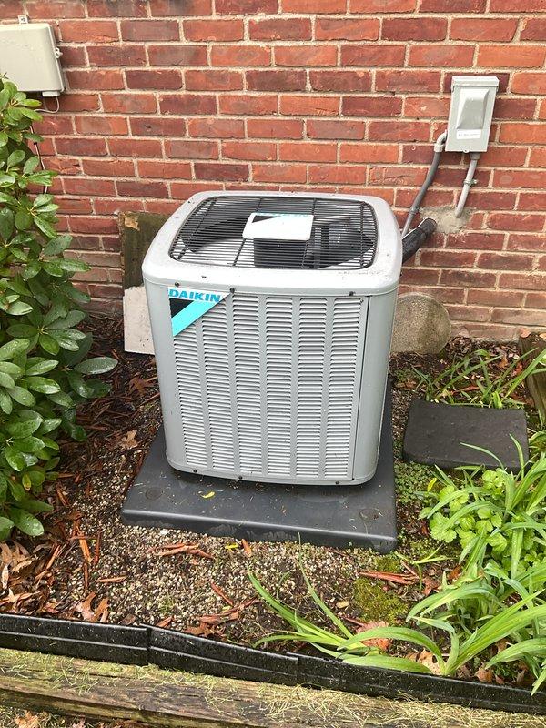 Completed comprehensive Gold AC inspection on a 5-year-old Daikin residential air conditioning system. Inspected outdoor condenser unit positioned on concrete pad against exterior brick wall, confirming proper clearances and adequate airflow around cabinet louvers. Verified electrical connections at disconnect box and assessed overall external condition of unit.

Accessed indoor air handler and evaporator coil assembly located in basement. During inspection, identified moderate dust and lint accumulation on evaporator coil surfaces, which is typical for equipment of this age. Photographed coil condition and noted buildup on metal heat exchanger fins. Inspected refrigerant line connections and brass valve fittings for proper sealing and signs of leakage.

Verified system operational status with homeowner present. Confirmed single-zone system is currently functioning as designed. Completed visual inspection of all accessible HVAC components, including protective grills, cabinet integrity