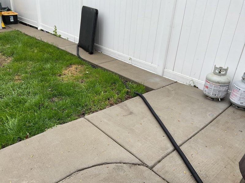 Responded to ongoing sump pump drainage issue affecting both basement interior and exterior discharge system in 47-year-old residential property. Inspected exterior discharge line and identified improper drainage configuration with corrugated flexible hose creating potential for water backup and freeze concerns. Relocated and secured exterior discharge piping away from foundation to ensure proper water evacuation and prevent recirculation into sump basin. Verified pump operation and discharge flow to exterior termination point. System now functioning correctly with improved drainage path to protect foundation and prevent basement water intrusion.