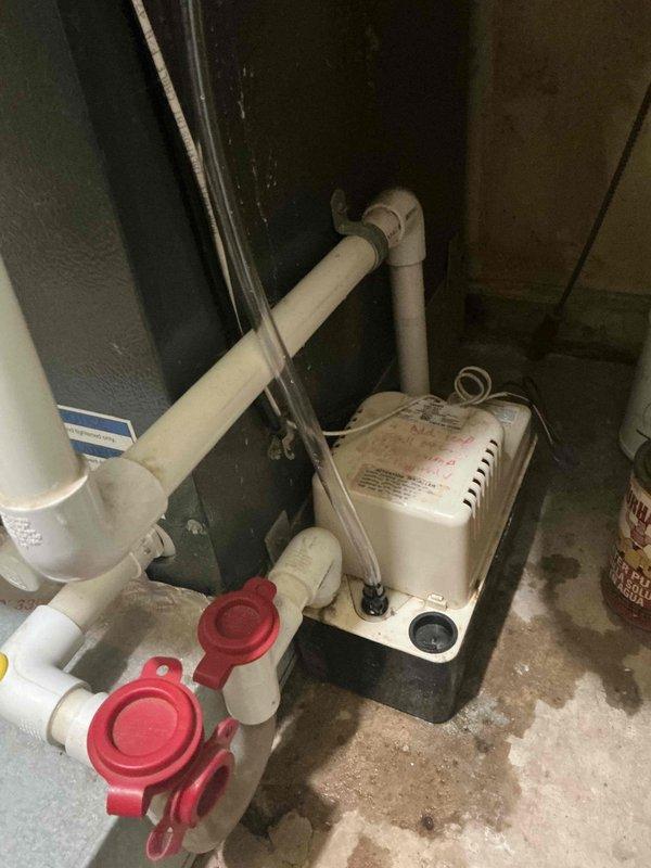 Responded to service call for 8-year-old air conditioning system with evaporator coil located in kitchen area. Performed diagnostic evaluation of condensate drainage system and identified deteriorated vinyl tubing on condensate pump requiring replacement. Assessed copper condensate line condition and recommended blowout service to ensure proper drainage flow. Inspected Aprilaire humidifier control unit and associated mechanical components in attic installation. Documented equipment condition with photos showing condensate pump assembly, PVC drainage piping with shutoff valves, HVAC ductwork, and copper tubing routing. Provided detailed estimate for replacement of vinyl condensate pump drain tubing and copper line service to prevent future water damage and maintain proper system operation.