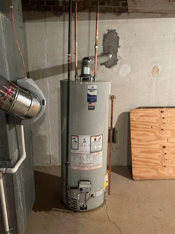 Completed standard installation of a 50-gallon Bradford White tanked water heater in basement utility area. Reconnected all copper supply and distribution lines to the new unit, ensuring proper connections at the top of the water heater with existing plumbing infrastructure. Verified all mechanical connections were secure and system was operational per manufacturer specifications.