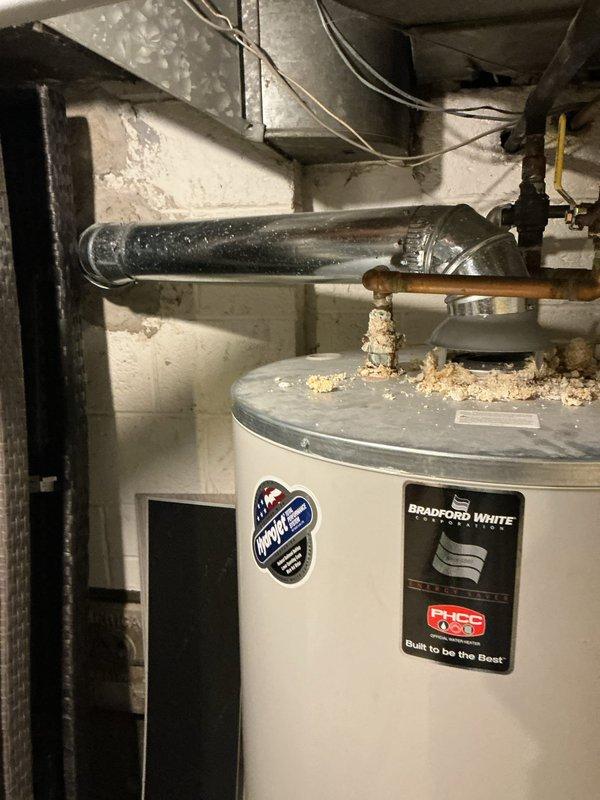 Responded to diagnostic request for Bradford White tanked water heater showing signs of corrosion as noted during previous service visit. Upon inspection, found significant accumulation of deteriorated insulation material and debris on top of unit around pipe connections. Examined copper supply lines and observed age-related oxidation and discoloration. Assessed overall condition of unit including top-mounted connections, piping integrity, and external surfaces for corrosion or deterioration. Documented findings with photographs showing debris accumulation and general equipment condition. Unit remains under full parts and labor warranty coverage.
