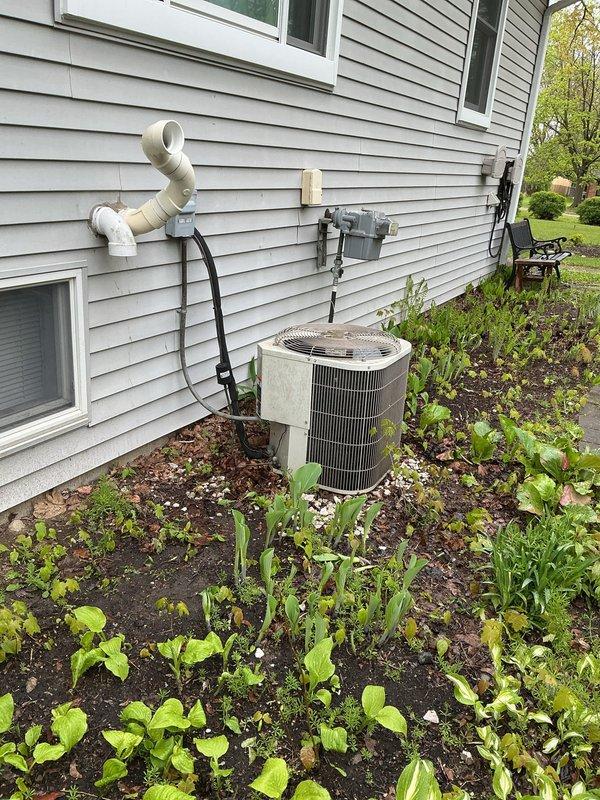 Completed HVAC system evaluation for replacement estimate on 25-year-old air conditioning system with basement-located coil and exterior condensing unit. System currently operational but utilizing R22 refrigerant, which is obsolete and no longer manufactured. Documented existing equipment configuration including outdoor condensing unit on concrete pad, PVC condensate drainage system with S-bend configuration mounted to exterior wall, electrical disconnect box, and utility connections. Assessed condition of aging components and provided comprehensive replacement options for complete system upgrade to modern, energy-efficient equipment with environmentally-compliant refrigerant.