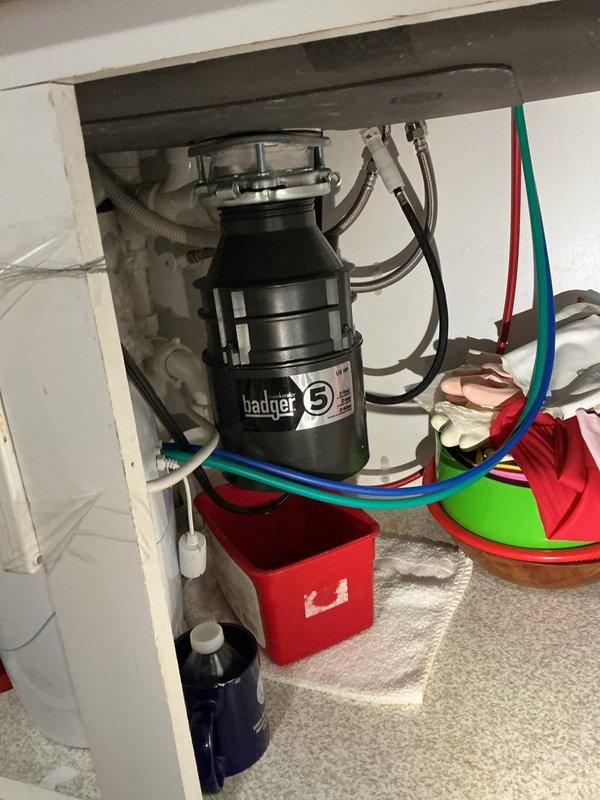Responded to a water leak originating from the kitchen sink area. Upon inspection, identified a steady leak from the Badger 5 garbage disposal unit mounted beneath the sink. Examined all plumbing connections, including the disposal mounting flange, discharge pipes, and associated PVC and flexible hose connections. Diagnosed the source of the leak, tightened loose connections, and verified proper seal integrity at the disposal unit. Tested the system for proper drainage and confirmed the leak was resolved with no further water discharge observed.