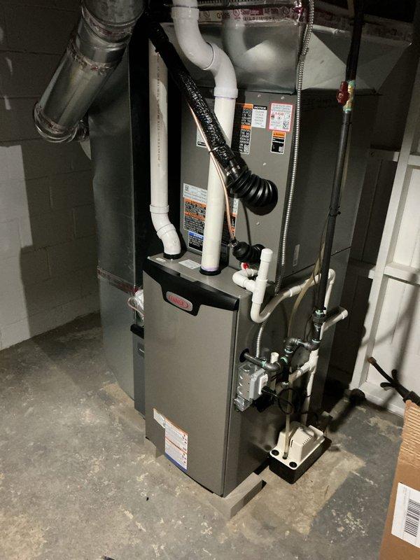 Performed seasonal AC startup and system inspection on residential HVAC unit. Accessed and examined furnace control board assembly, verifying proper operation of electronic components, capacitors, and digital display indicators. Confirmed all wire connections at terminal blocks were secure and all safety controls were functioning correctly. Inspected complete furnace installation including PVC condensate drain lines, combustion air intake/exhaust venting, and condensate pump operation. System tested and confirmed operational for cooling season.