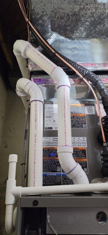Completed full HVAC system replacement including removal of existing low boy furnace and installation of new 70,000 BTU furnace with 2-ton air conditioning unit configured for right-side placement. Installed new thermostat, humidifier, and liner as part of the complete system upgrade. Configured white PVC condensate drainage system with proper pitch and secure connections using purple primer, running both vertical and horizontal lines to ensure efficient moisture removal. Installed copper refrigerant lines with appropriate insulation and flexible metal conduit for electrical connections. Mounted control panel and wiring in compliance with mechanical and electrical permit requirements. System achieved AHRI certification number 21558462, qualifying for utility rebate program. All components properly secured and labeled with specification plates and safety warnings. Installation completed in unfinished utility space with drainage system terminating at flush mount pump kit for condensate r