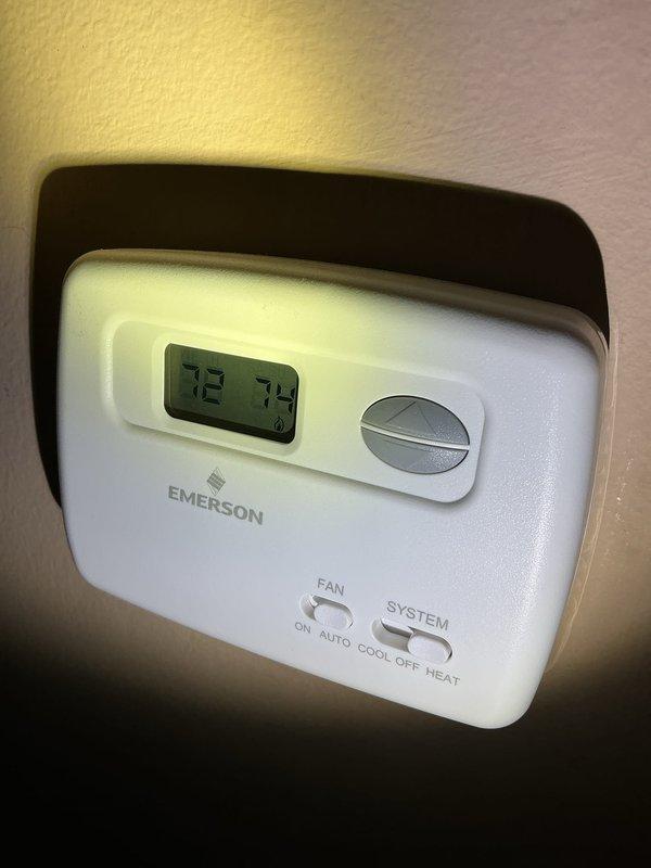 Responded to service call for 10-month-old AC unit in basement with no heating or cooling capability, though blower motor was operational. Performed diagnostic evaluation and identified malfunctioning control board as root cause of system failure. Accessed control board assembly housed in black plastic enclosure, inspecting circuit boards, wiring connections, and terminal blocks. Verified thermostat communication and settings showing 72-degree setpoint on Emerson unit. Replaced defective mitigation board, ensuring all wire connections were properly secured to terminal blocks and system controls were functioning correctly. Tested system operation to confirm restoration of heating and cooling functions.