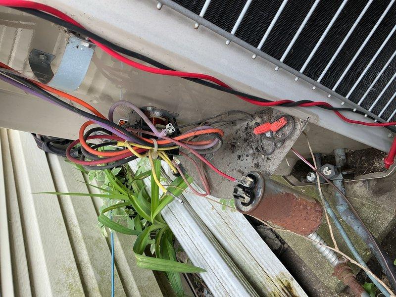 Completed comprehensive Gold AC Inspection on a 20+ year old single-unit air conditioning system with air handler located in basement. Performed thorough visual examination of outdoor condensing unit positioned on elevated deck mounting, inspecting compressor, condenser coil fins, electrical connections, and refrigerant lines. Evaluated electrical wiring connections and terminal blocks for proper voltage and secure terminations. Assessed condensate drainage system and PVC drain lines for proper function. Inspected unit for signs of wear, corrosion, and environmental damage consistent with age of equipment. Verified system operational status and confirmed unit functioning properly at time of inspection. Documented equipment condition through photographic evidence showing exterior condensing unit placement, electrical connections, and surrounding installation area.