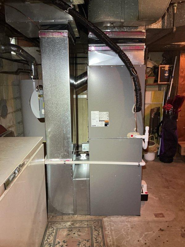 Completed comprehensive Gold AC inspection on a 1-year-old residential HVAC system with air handler located in basement. All equipment found in proper working condition. Inspected air handler unit, ductwork connections, condensate drain line with functioning valve, and Honeywell Home ProSeries thermostat set at 72 degrees. Verified system operation, checked all accessible components including metal supply and return ducts, flexible duct connections, and PVC drain piping. Unit operating within normal parameters with no deficiencies noted. Documented system condition with photographs for service records.
