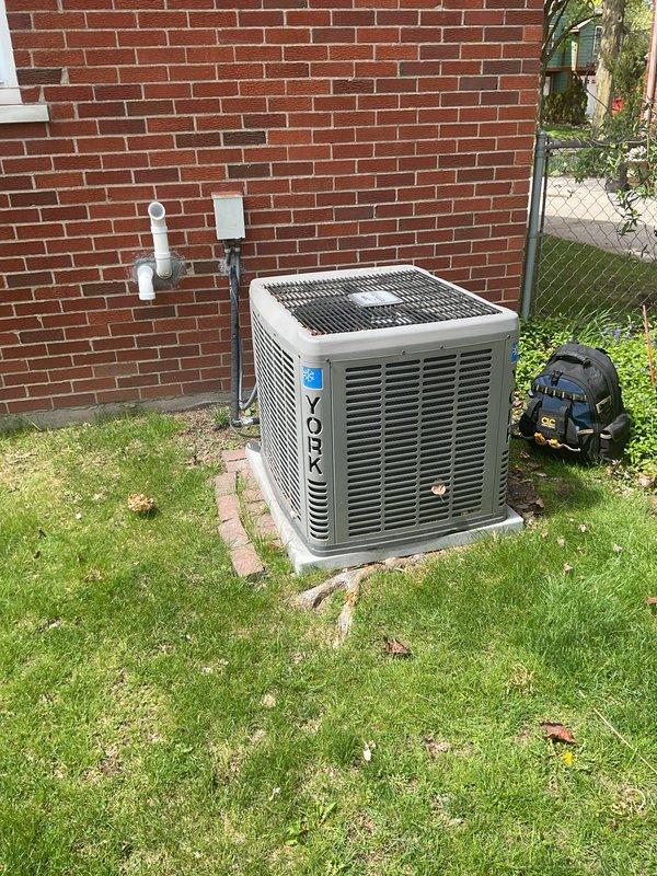Completed comprehensive Gold AC inspection on 8-year-old York residential cooling system with air handler located in basement. Performed full system evaluation including indoor and outdoor unit assessment, verified operational status of all components, checked refrigerant lines and electrical connections, inspected condensate drainage system with white PVC piping, and examined ductwork connections. System found to be in proper working order with no immediate service requirements identified. Applied approved certification sticker to indoor unit upon completion of inspection protocol.