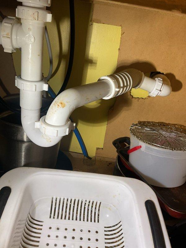 Responded to kitchen sink backup in 111-year-old home. Accessed plumbing system through crawlspace to inspect drainage configuration and P-trap assembly beneath sink. Cleared obstruction from drainage line, verified proper flow through PVC trap assembly and corrugated drain line connections. Tested system to ensure complete drainage restoration and confirmed all connections were secure with no leaks present.