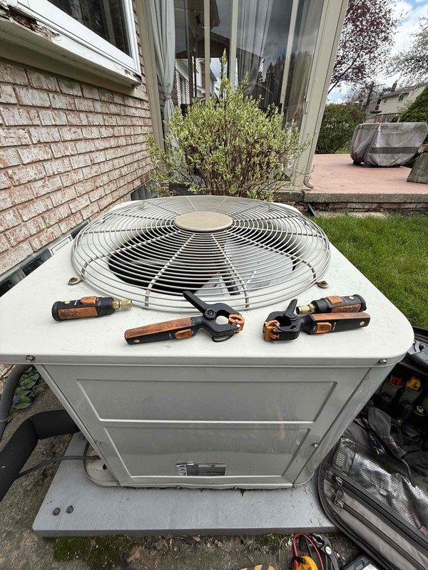 Completed comprehensive tune-up on 20-year-old air conditioning system with outdoor condenser unit and basement air handler. Performed standard maintenance protocol including refrigerant pressure check using manifold gauges, inspected electrical connections, cleaned condenser coils, and verified proper system operation. Identified water accumulation on basement floor near equipment, indicating potential condensate drain line issue or secondary drain pan overflow that will require monitoring or future service to prevent water damage.