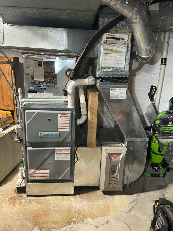 # Summary

Completed comprehensive Gold AC inspection on 1-year-old Daikin HVAC system with Lennox coil unit located in basement. Performed multi-point system evaluation including visual inspection of furnace, air handler, ductwork connections, refrigerant lines, condensate drainage, and electrical components, verifying proper installation and operational status of all equipment.

# Work Performed

Conducted thorough Gold-level air conditioning inspection on residential forced-air heating and cooling system. Inspected Daikin furnace unit (gray/silver housing) and Lennox coil unit model CK40UT-48C-71, serial number 1524M39772, both located in basement utility area. Verified homeowner presence and confirmed equipment operational prior to inspection.

Performed visual assessment of all accessible HVAC components including metallic ductwork connections, copper refrigerant lines, and air handler assembly. Examined furnace front panel labels, warning stickers, and specification plates for pr