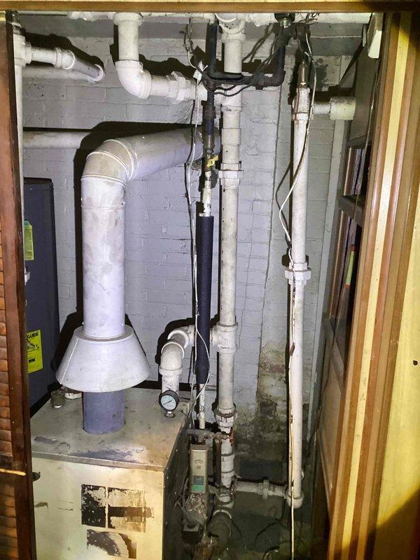 Provided estimate for replacement of non-functional hot water boiler system located in basement utility area. Current equipment is over 10 years old and no longer operational, with visible signs of water damage and moisture issues on concrete floor surrounding the unit. Assessment included evaluation of existing venting system, plumbing connections, and electrical service to determine replacement specifications and installation requirements.
