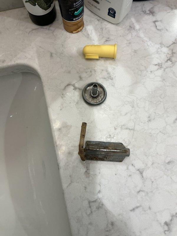 Responded to service call for non-functioning bathroom faucet. Upon inspection, discovered severely corroded faucet supply line and deteriorated mounting hardware beneath sink. Removed failed components showing extensive rust damage and mineral buildup that had compromised water flow and fixture operation. Installed new chrome drain assembly, replaced P-trap with white PVC piping, and connected new braided stainless steel flexible supply lines to restore proper water delivery to faucet. Verified all connections for leaks, confirmed proper drainage function, and tested hot and cold water flow to ensure complete restoration of fixture operation.