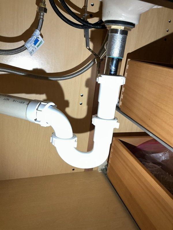 Responded to service call for non-functioning bathroom faucet. Upon inspection, discovered severely corroded faucet supply line and deteriorated mounting hardware beneath sink. Removed failed components showing extensive rust damage and mineral buildup that had compromised water flow and fixture operation. Installed new chrome drain assembly, replaced P-trap with white PVC piping, and connected new braided stainless steel flexible supply lines to restore proper water delivery to faucet. Verified all connections for leaks, confirmed proper drainage function, and tested hot and cold water flow to ensure complete restoration of fixture operation.