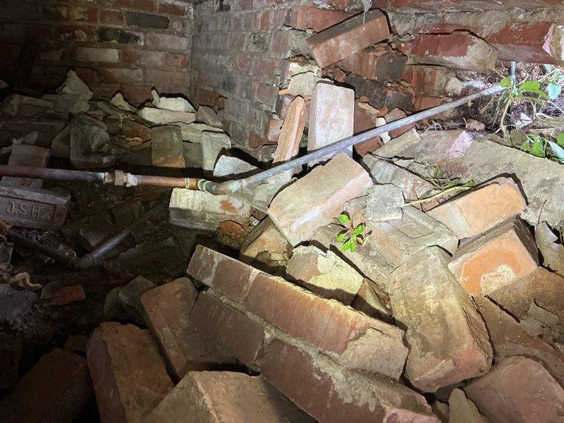 Responded to service call for leaking outdoor spigot. Upon arrival, discovered extensive structural deterioration of foundation wall surrounding the exterior water supply line. The brick foundation showed severe collapse with compromised mortar joints, displaced bricks, and multiple voids exposing interior cavities. The copper supply pipe exhibited significant corrosion and was routed through the damaged masonry structure. Due to the catastrophic failure of the supporting foundation and unsafe structural conditions, the outdoor spigot repair could not be completed as originally requested. Documented extensive damage with photographs showing fallen brickwork, deteriorated mortar, and exposed piping. Recommended immediate consultation with structural engineer and masonry contractor to assess foundation stability before any plumbing repairs can be safely performed.