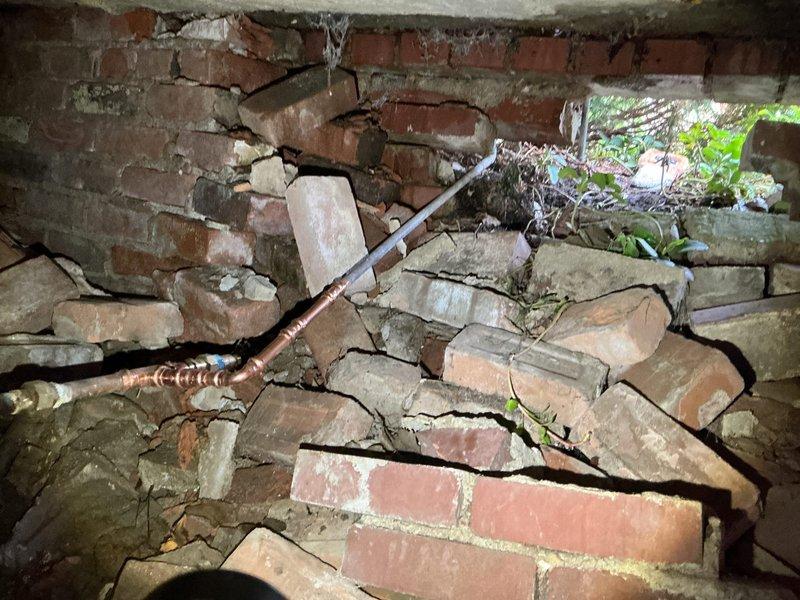 Responded to service call for leaking outdoor spigot. Upon arrival, discovered extensive structural deterioration of foundation wall surrounding the exterior water supply line. The brick foundation showed severe collapse with compromised mortar joints, displaced bricks, and multiple voids exposing interior cavities. The copper supply pipe exhibited significant corrosion and was routed through the damaged masonry structure. Due to the catastrophic failure of the supporting foundation and unsafe structural conditions, the outdoor spigot repair could not be completed as originally requested. Documented extensive damage with photographs showing fallen brickwork, deteriorated mortar, and exposed piping. Recommended immediate consultation with structural engineer and masonry contractor to assess foundation stability before any plumbing repairs can be safely performed.