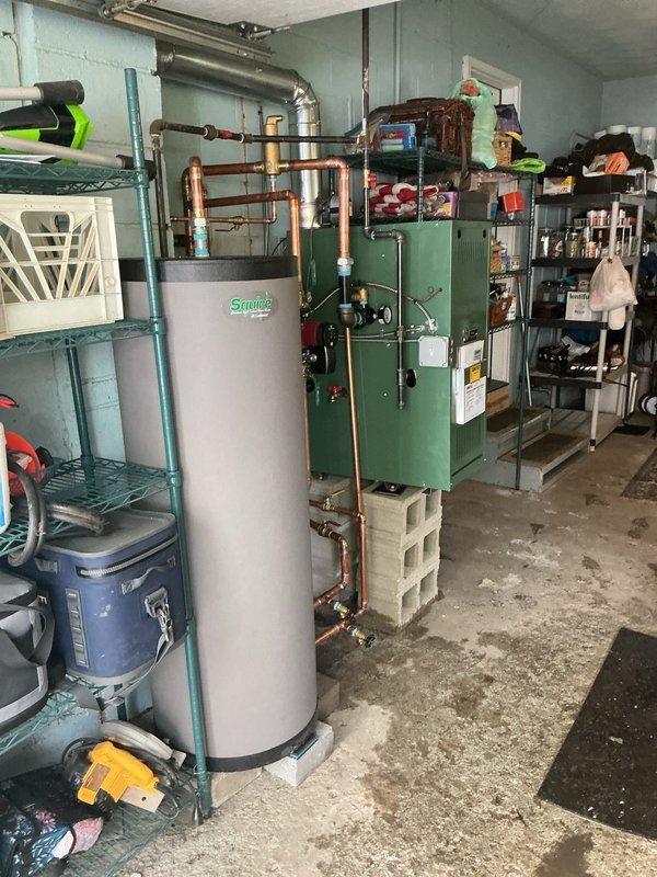 Completed installation and reconnection of green boiler system with associated hydronic piping network, including copper distribution lines, red circulator pump, brass fittings, and expansion tank. Integrated Squire indirect water heater into system with proper piping connections and blue insulation on supply lines. Verified thermostat operation, checked all boiler functions, and ensured proper system startup after mechanical permit approval and reconnection work.