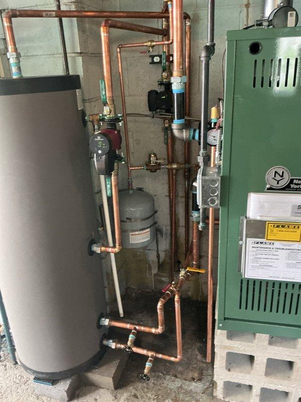 Completed installation and reconnection of green boiler system with associated hydronic piping network, including copper distribution lines, red circulator pump, brass fittings, and expansion tank. Integrated Squire indirect water heater into system with proper piping connections and blue insulation on supply lines. Verified thermostat operation, checked all boiler functions, and ensured proper system startup after mechanical permit approval and reconnection work.