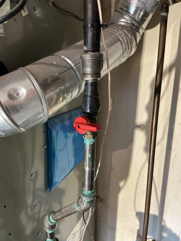 Responded to emergency gas leak situation where utility company had shut off gas supply to 1957-built residence. Located and repaired corroded gas line connection in laundry room at point of entry from exterior, replaced deteriorated threaded fittings and valve assembly showing significant oxidation and green patina typical of aged brass components. Performed pressure test on repaired section to verify integrity of repair and ensure no additional leaks present in system. Restored gas service to residence, returning heating system to operational status.