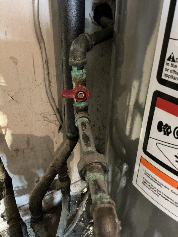 Responded to emergency gas leak situation where utility company had shut off gas supply to 1957-built residence. Located and repaired corroded gas line connection in laundry room at point of entry from exterior, replaced deteriorated threaded fittings and valve assembly showing significant oxidation and green patina typical of aged brass components. Performed pressure test on repaired section to verify integrity of repair and ensure no additional leaks present in system. Restored gas service to residence, returning heating system to operational status.