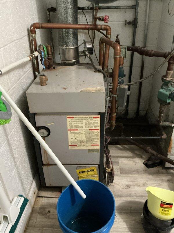 Provided estimate for natural gas boiler replacement in utility room. Current 10+ year old unit is non-operational with visible signs of aging throughout the system, including oxidized copper piping, multiple circulator pumps, and complex valve configurations. Documented existing mechanical room setup including expansion tank, zone valves, and associated plumbing components to prepare comprehensive replacement proposal.
