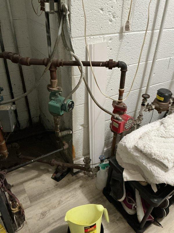 Provided estimate for natural gas boiler replacement in utility room. Current 10+ year old unit is non-operational with visible signs of aging throughout the system, including oxidized copper piping, multiple circulator pumps, and complex valve configurations. Documented existing mechanical room setup including expansion tank, zone valves, and associated plumbing components to prepare comprehensive replacement proposal.