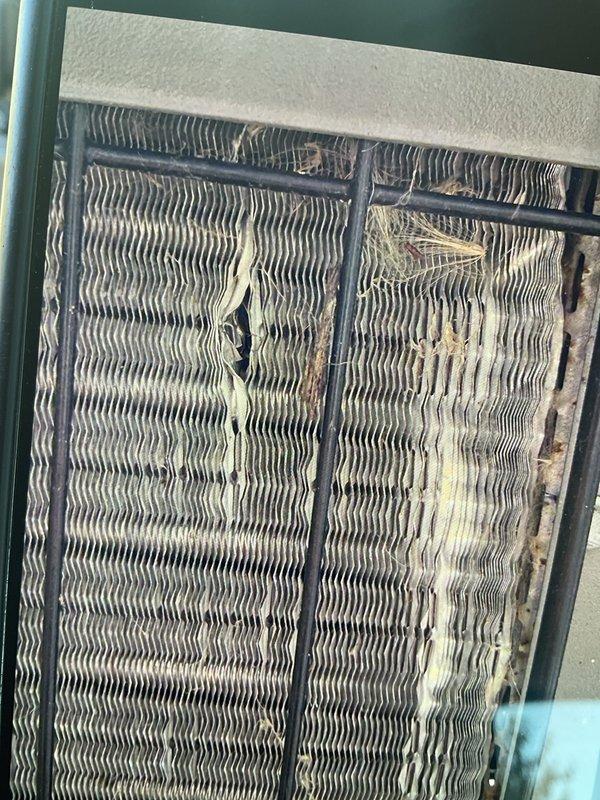 Completed Gold AC Inspection on 16-year-old Lennox air conditioning system with outdoor condenser unit and first floor closet air handler. Performed comprehensive system evaluation including visual inspection of condenser unit, which showed dirt accumulation on top panel and surrounding area requiring debris clearance. Evaporator coil inspection revealed heavy soiling with significant dust, dirt, and debris buildup throughout finned surfaces, along with cobweb accumulation affecting airflow efficiency. Documented equipment condition through photographic evidence showing condenser unit positioning on grade with proper clearances and electrical disconnect box mounting. Advised customer on necessary maintenance recommendations including condenser area clearance from debris and animal waste, and noted evaporator coil cleaning requirements to restore optimal system performance and efficiency.