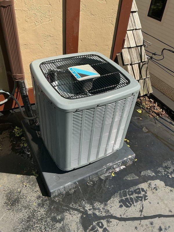 # HVAC Maintenance - Gold AC Inspection

Completed comprehensive Gold-level air conditioning inspection on two outdoor condensing units, both under 10 years of age. Performed thorough visual assessment, operational testing, and diagnostic evaluation of both systems. Documented equipment condition through photographic records showing both units positioned on concrete pads against exterior building wall with proper clearances maintained.

## Inspection Activities Performed

**Unit 1 Assessment:**
- Inspected outdoor condensing unit with light gray metal cabinet and vertical louvered ventilation panels
- Verified protective fan grille integrity and proper installation
- Assessed concrete pad condition, noting weathering and surface deterioration with moss/algae growth
- Checked refrigerant line connections and electrical terminations
- Evaluated unit positioning and clearances from surrounding structures including wooden trim and lattice screening
- Confirmed adequate drainage around unit
