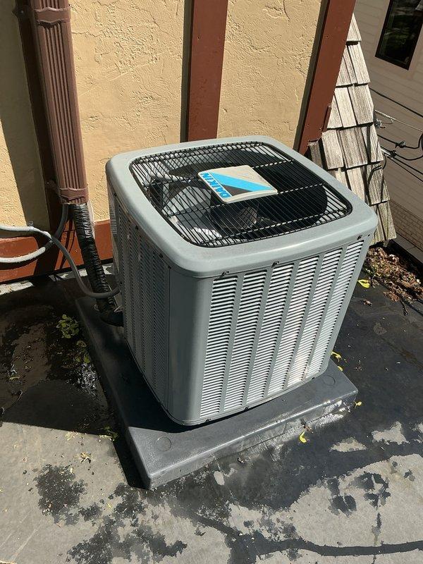 # HVAC Maintenance - Gold AC Inspection

Completed comprehensive Gold-level air conditioning inspection on two outdoor condensing units, both under 10 years of age. Performed thorough visual assessment, operational testing, and diagnostic evaluation of both systems. Documented equipment condition through photographic records showing both units positioned on concrete pads against exterior building wall with proper clearances maintained.

## Inspection Activities Performed

**Unit 1 Assessment:**
- Inspected outdoor condensing unit with light gray metal cabinet and vertical louvered ventilation panels
- Verified protective fan grille integrity and proper installation
- Assessed concrete pad condition, noting weathering and surface deterioration with moss/algae growth
- Checked refrigerant line connections and electrical terminations
- Evaluated unit positioning and clearances from surrounding structures including wooden trim and lattice screening
- Confirmed adequate drainage around unit