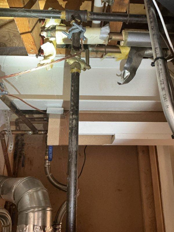 Responded to no hot water complaint at 54-year-old residence with 9-year-old water heater in basement. Upon arrival, confirmed water heater was cool to the touch and not producing hot water since previous evening. Performed diagnostic inspection of unit, including examination of gas supply line, pilot light assembly, thermocouple, gas control valve, and venting system. Verified proper gas flow to unit and checked all safety mechanisms and electrical connections. Inspected flue pipe and draft hood for proper ventilation and clearances. Documented current condition of water heater installation with photos showing unit positioning, piping connections, Energy Star rated tank, and overhead gas line configuration with brass fittings. Assessed overall system integrity including copper supply lines, shut-off valves, and temperature-pressure relief valve operation.