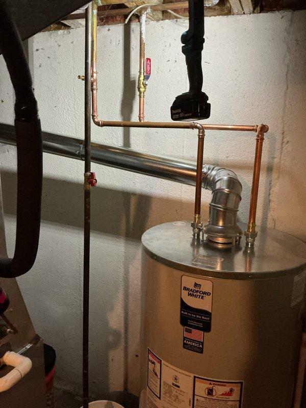 Completed installation of a 50-gallon short Bradford White tanked water heater in basement utility area. Reconnected all copper supply lines, installed brass shut-off valves with proper venting configuration, and verified system operation with no leaks detected.