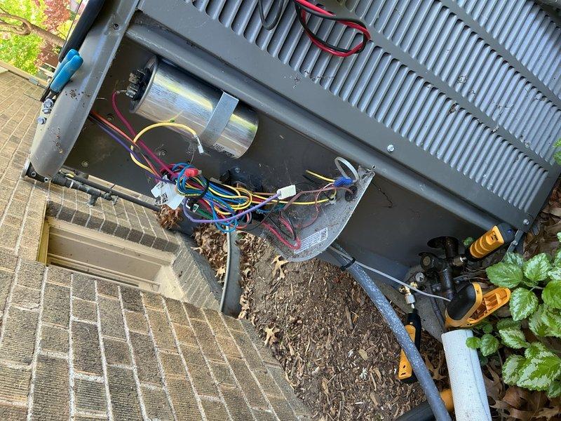 Completed comprehensive Gold AC inspection on 3-year-old residential air conditioning system at primary residence. Performed thorough examination of outdoor condenser unit, including inspection of electrical components, capacitor, wiring connections, and terminal blocks. Assessed internal cleanliness and noted accumulated debris including leaves and dirt in unit base. Verified proper operation of fan assembly and examined cooling fins and heat exchanger components. Documented equipment condition through detailed photography showing unit interior and exterior placement on concrete pad adjacent to building structure. System found to be operational with homeowner present during inspection.