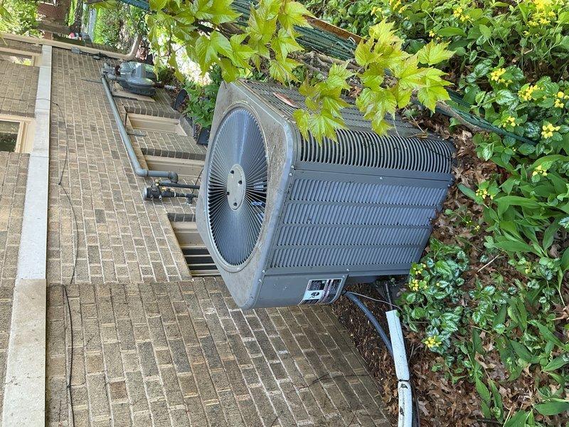 Completed comprehensive Gold AC inspection on 3-year-old residential air conditioning system at primary residence. Performed thorough examination of outdoor condenser unit, including inspection of electrical components, capacitor, wiring connections, and terminal blocks. Assessed internal cleanliness and noted accumulated debris including leaves and dirt in unit base. Verified proper operation of fan assembly and examined cooling fins and heat exchanger components. Documented equipment condition through detailed photography showing unit interior and exterior placement on concrete pad adjacent to building structure. System found to be operational with homeowner present during inspection.
