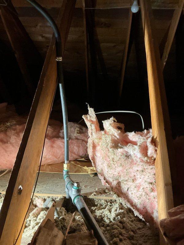 Completed comprehensive re-pipe of residential water supply system, including replacement of deteriorated piping from attic distribution lines through wall cavity to bathroom fixtures. Removed old galvanized supply lines and installed new copper piping with brass compression fittings and quarter-turn shutoff valves. Accessed supply lines through attic space by carefully navigating around existing insulation and roof structure, then ran new water lines vertically down through wall cavity to bathroom fixture locations. Cut access openings in tile wall to expose connection points and installed new valve assembly with red-handle shutoff control and flexible supply line connector. Tested all connections for leaks and proper water pressure upon completion. Restored insulation placement in attic workspace and prepared wall openings for finish work.