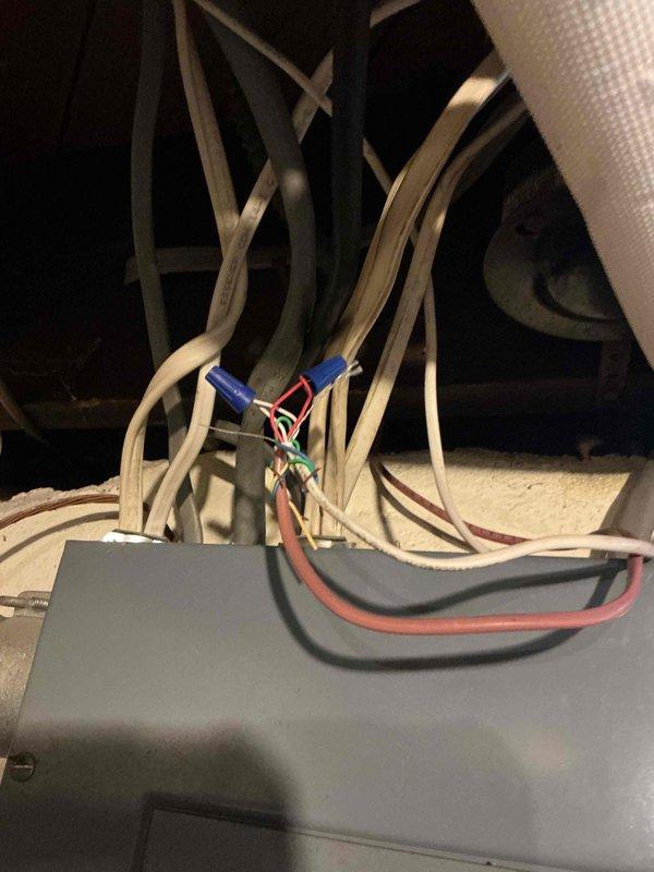 Responded to service call for 4-year-old Lennox AC unit not working properly due to wiring issue. Diagnosed faulty electrical connections at the control box located in attic space near basement coil. Identified compromised wire connections with improper terminations at the electrical control unit. Repaired and secured all wiring connections, including red and black conductors with proper wire nuts, ensuring secure terminations and code-compliant installation. Verified system operation and confirmed proper electrical flow to condenser unit positioned at exterior brick wall. Unit restored to full operational status.