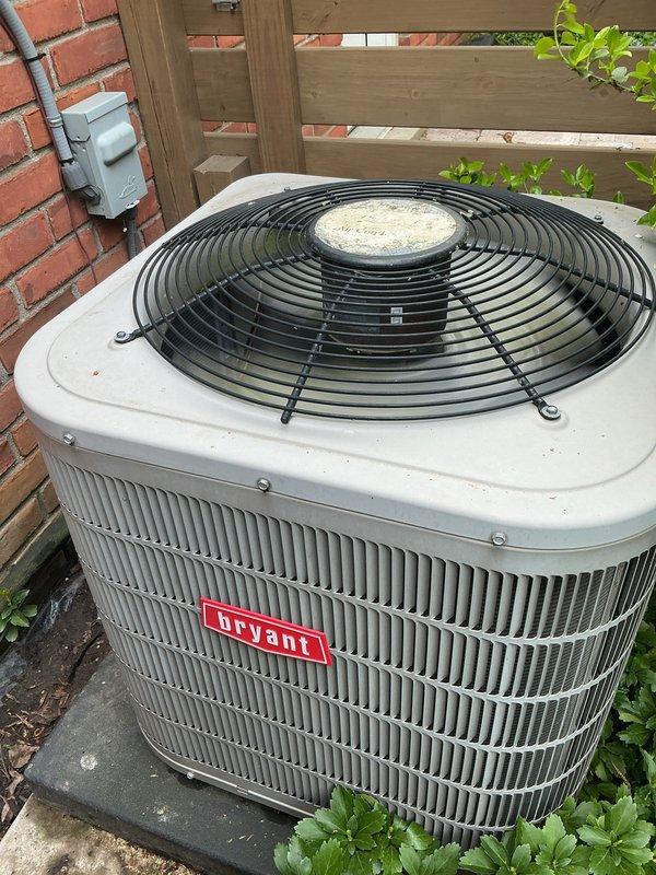 Completed comprehensive Gold AC Inspection on residential property with two Bryant condensing units, both over 10 years old, with air handler located in basement. Performed thorough visual inspection of both outdoor condensing units positioned on concrete pads in backyard area. Units were operational at time of service. Inspected condenser coils, fan assemblies, cabinet condition, and electrical disconnect boxes. Verified proper clearance around equipment and assessed overall system condition. Documented equipment condition through photographic records showing units mounted on concrete pads with adequate drainage, proper installation against brick wall structure, and maintained clearances from surrounding vegetation and fencing. Both systems showed normal operational wear consistent with age, with minor surface soiling present on exterior cabinets. All safety components including fan guards were intact and properly secured.